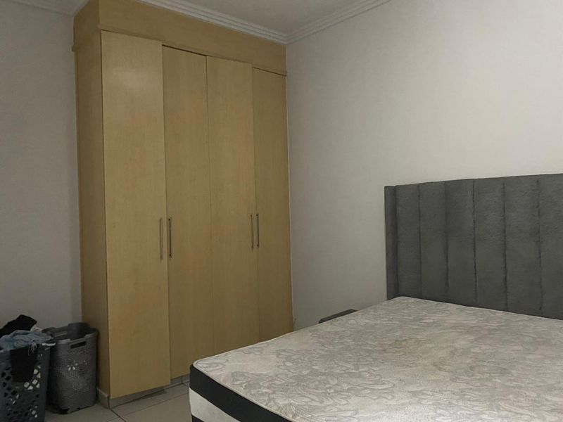 A bedroom featuring a large built-in wooden wardrobe with modern handles and decorative ceiling coving.