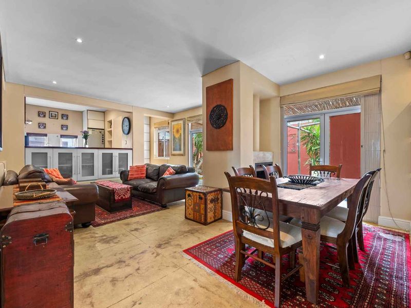 Spacious open-plan living and dining area featuring a fireplace, built-in shelving, and direct access to an outdoor space through sliding glass doors.