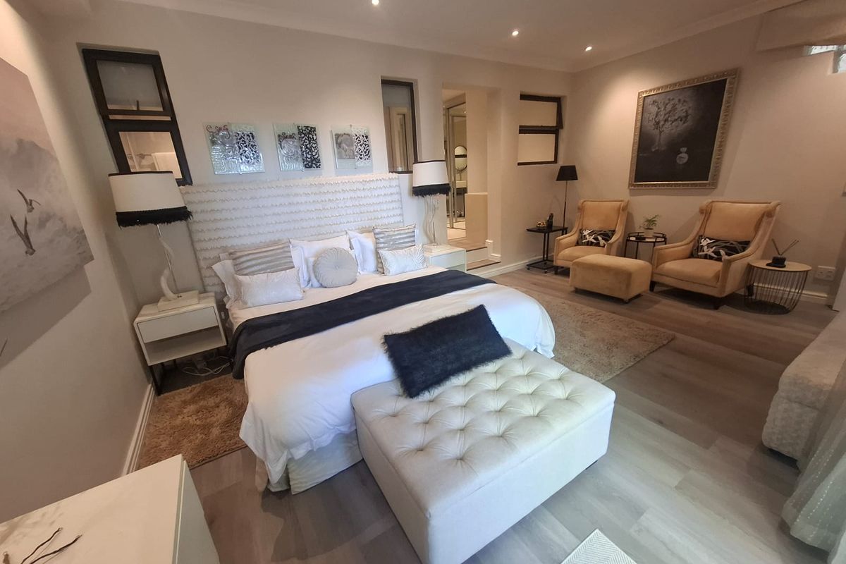 Spacious master bedroom featuring modern laminate flooring, recessed downlighting, and an integrated en-suite bathroom layout.