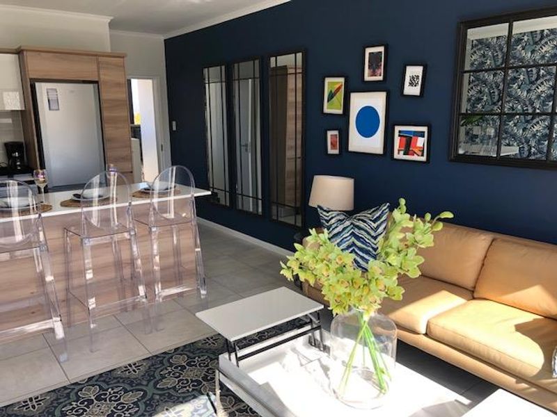 An open-plan living and kitchen area featuring modern cabinetry, stone countertops, and tiled flooring, creating a cohesive and functional living space.