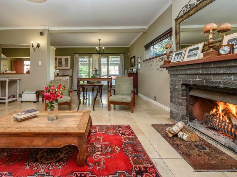 Spacious open-plan living and dining area featuring a prominent brick fireplace, tiled flooring, and a convenient pass-through window to the kitchen.