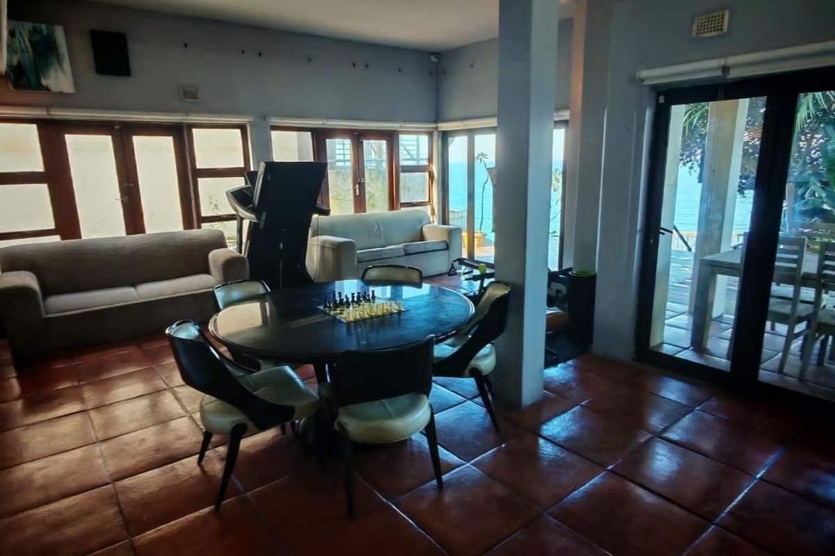 Spacious living area featuring terracotta floor tiles, exposed ceiling beams, and large sliding glass doors providing natural light and access to the outdoor area.
