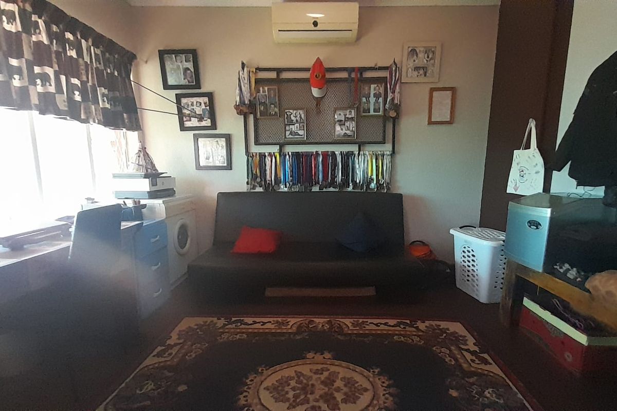 A multi-purpose bedroom space featuring a wall-mounted split-system air conditioner and large window providing natural light.