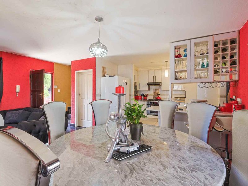 Open-plan living and dining area featuring a functional kitchen with built-in cabinetry, extractor fan, and integrated wine storage, finished with tiled flooring.