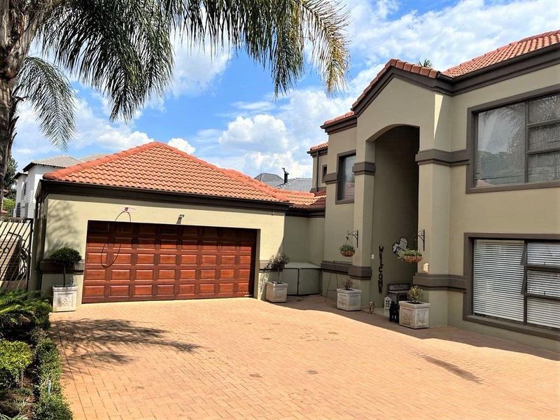 Front elevation of a well-maintained double-story home featuring a paved driveway, double garage, and tiled roof.