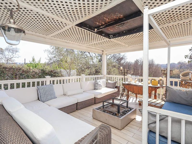 Covered outdoor patio featuring timber decking, a lattice ceiling, and protective railings, offering a functional space for outdoor relaxation and entertainment.