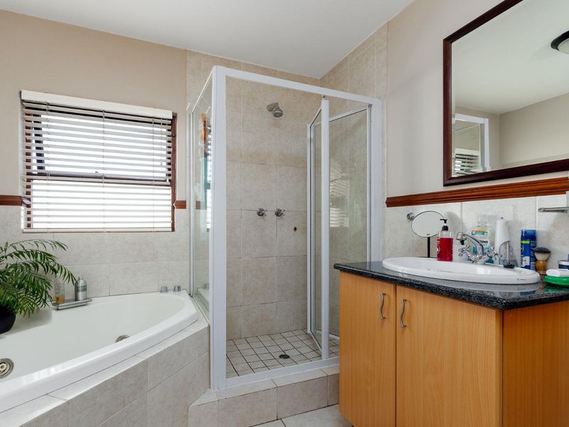 A functional bathroom featuring a corner bathtub, separate shower enclosure, and a vanity cabinet with a granite countertop.