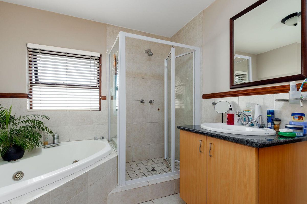 A functional bathroom featuring a corner bathtub, separate shower enclosure, and a vanity cabinet with a granite countertop.