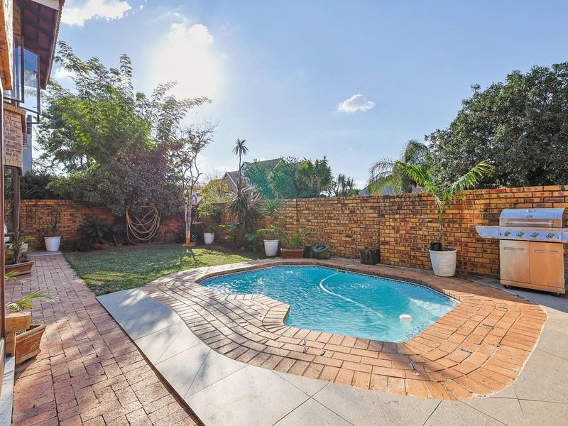 Private rear garden featuring a swimming pool, paved patio area, and a built-in gas braai, enclosed by a brick boundary wall.