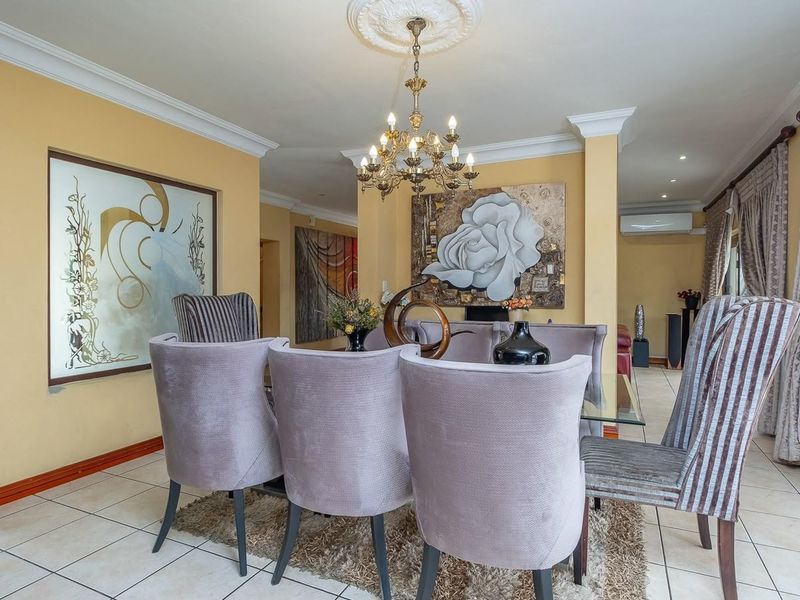 Spacious dining area featuring tiled flooring, crown molding, a decorative ceiling rose with a chandelier, and direct access to the patio via sliding glass doors.