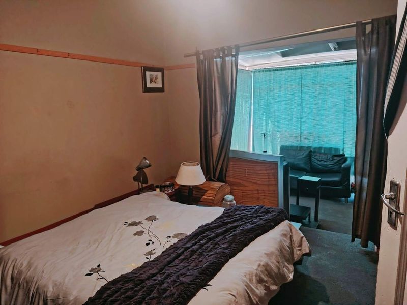Bedroom featuring a bay window area with a timber partition, offering a distinct space for a seating area or study nook.