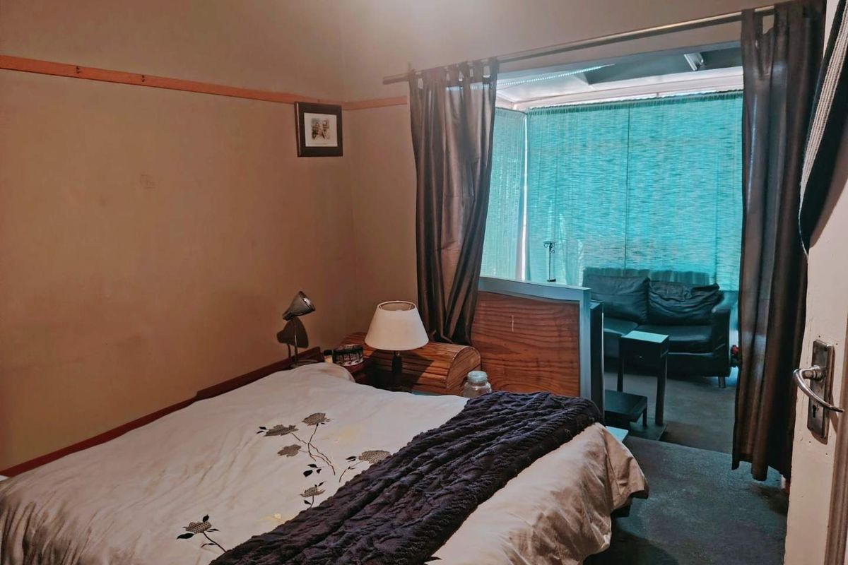 Bedroom featuring a bay window area with a timber partition, offering a distinct space for a seating area or study nook.