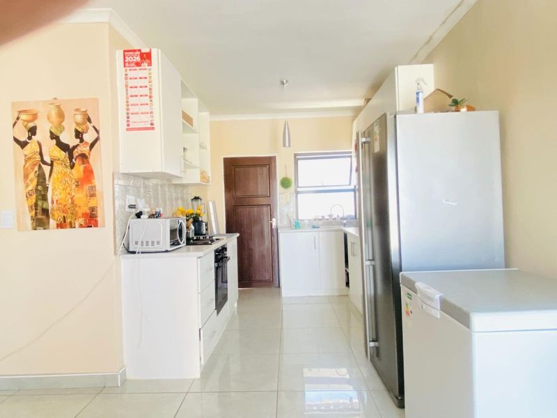 A functional kitchen featuring white built-in cabinetry, tiled flooring, a built-in oven, and a tiled backsplash, providing a clean and practical workspace.