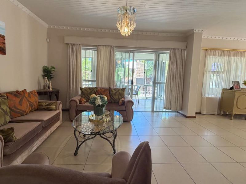 Spacious living room featuring large sliding glass doors leading to the patio, tiled flooring, and a decorative tongue and groove ceiling with crown molding.