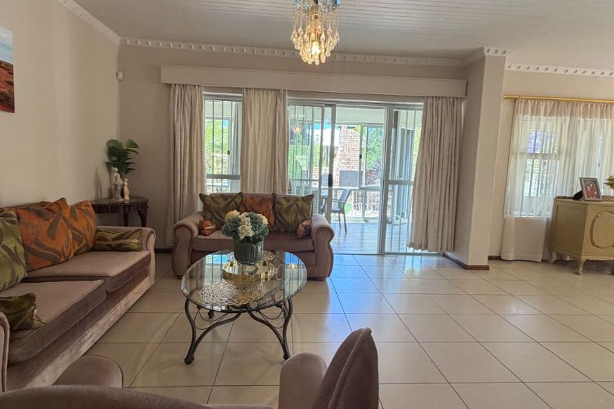 Spacious living room featuring large sliding glass doors leading to the patio, tiled flooring, and a decorative tongue and groove ceiling with crown molding.