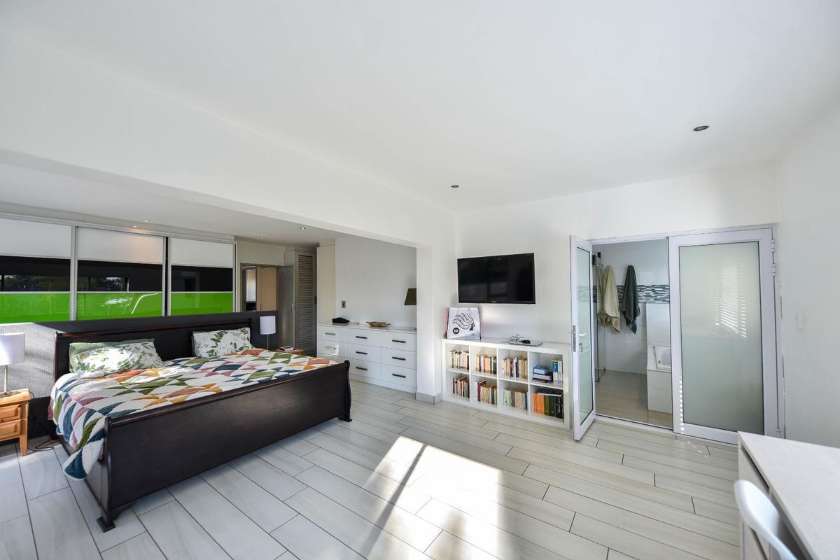 Spacious bedroom featuring light-toned tiled flooring, built-in storage, and direct access to an en-suite bathroom with modern finishes.