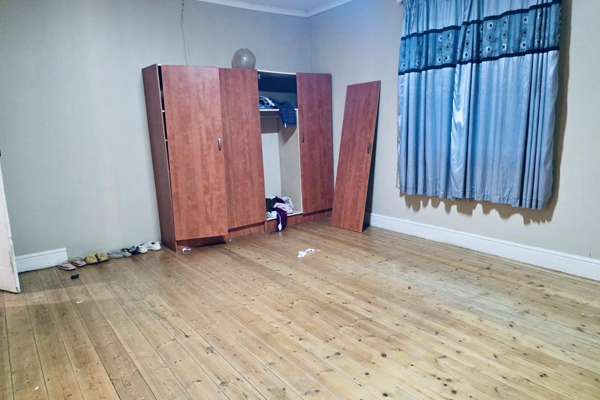 A bedroom featuring original timber flooring, skirting boards, and cornice, currently requiring cosmetic updates and repairs to the built-in wardrobe.