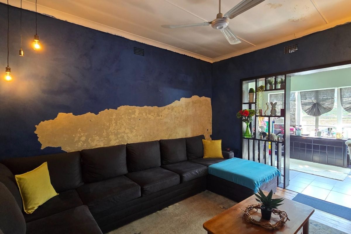 Living room featuring a built-in room divider and ceiling fan, currently requiring significant wall and ceiling repairs due to visible surface damage.