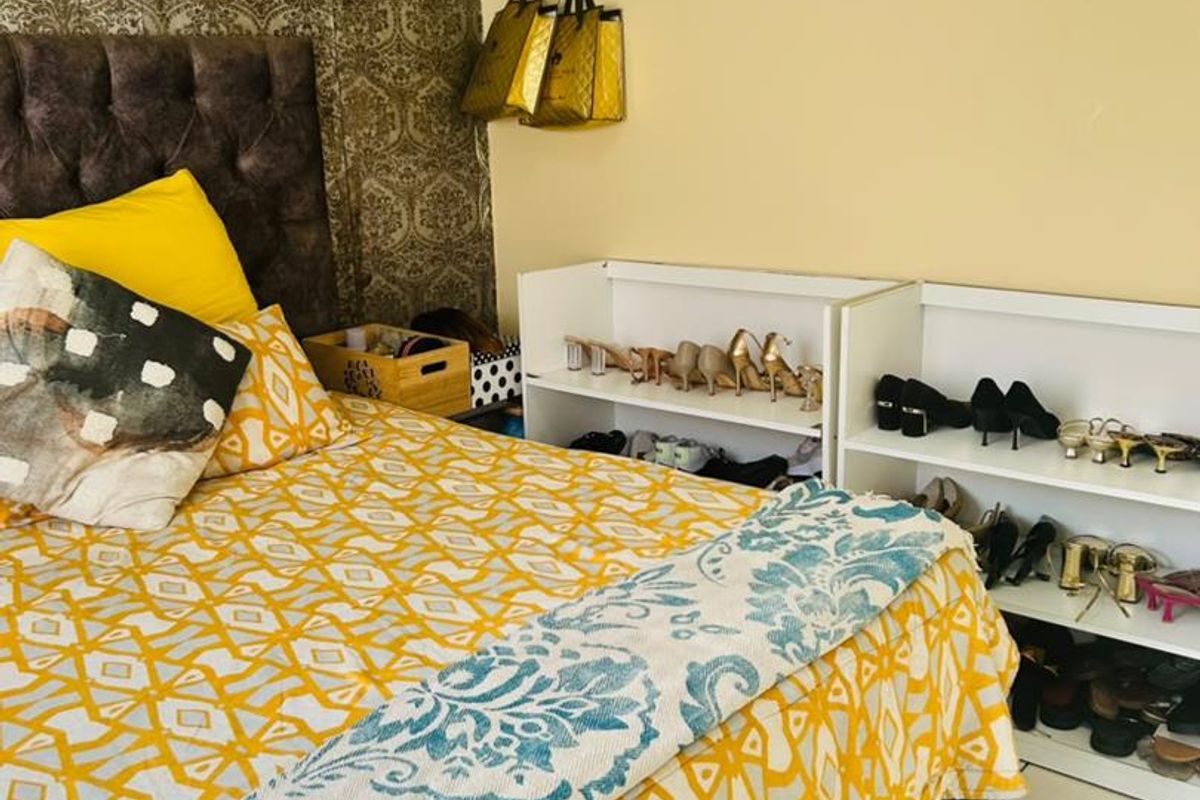 A bedroom featuring tiled flooring and a decorative feature wallpaper wall, providing a functional sleeping space.