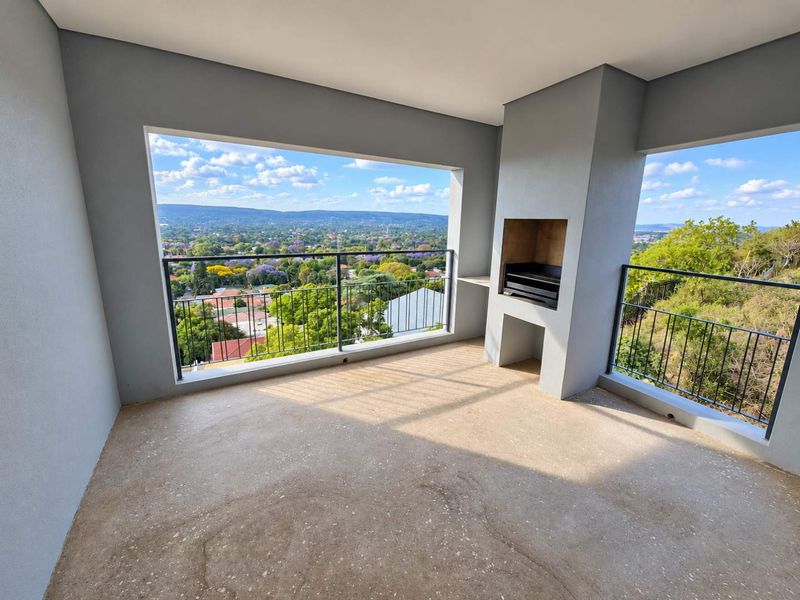 Spacious covered balcony featuring a built-in braai, metal balustrades, and expansive elevated views over the surrounding neighborhood.