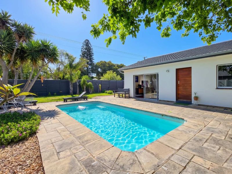 A well-maintained outdoor pool area featuring stone paving, a clear swimming pool, and direct access to the home via sliding glass doors.