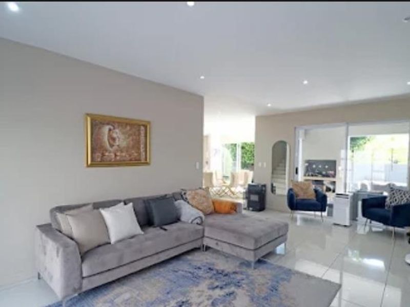 Spacious open-plan living area featuring modern porcelain floor tiles, recessed downlighting, and large sliding glass doors providing natural light and garden access.