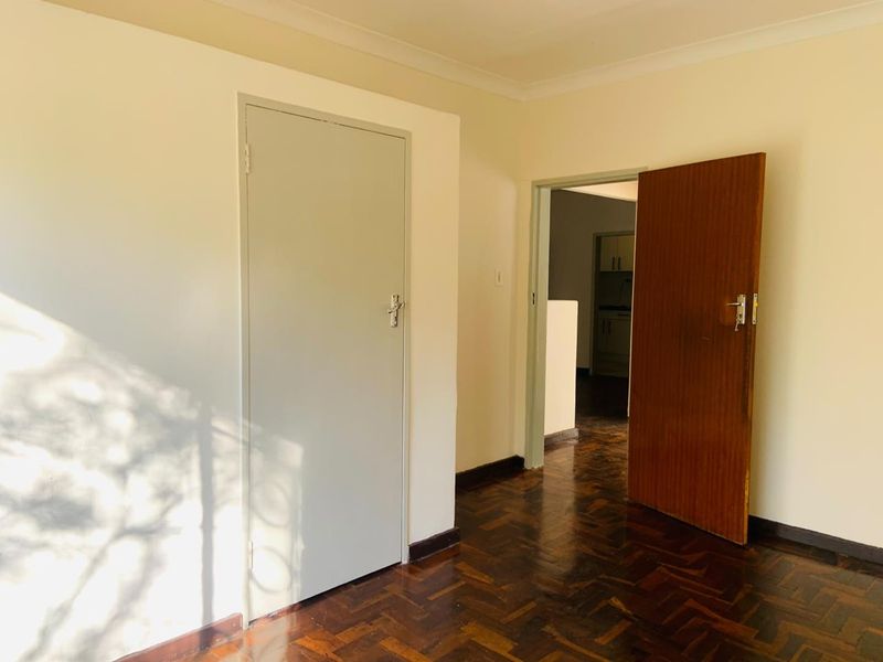 A vacant hallway featuring traditional parquet flooring and neutral wall finishes, providing access to adjacent rooms within the apartment.