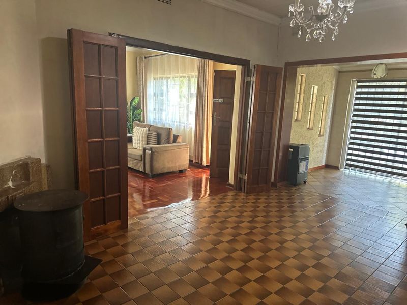 Spacious living area featuring classic parquet and checkerboard tiled flooring, elegant french doors, and a traditional crystal chandelier.