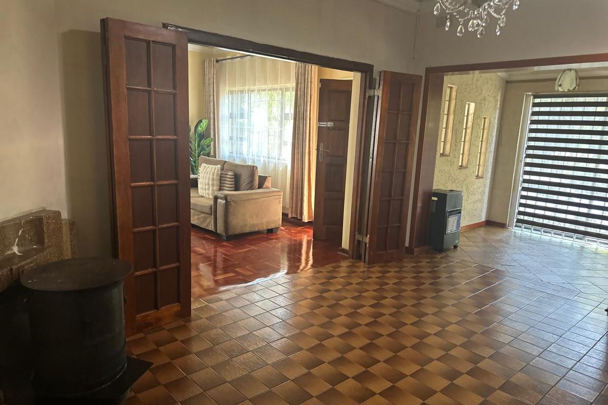 Spacious living area featuring classic parquet and checkerboard tiled flooring, elegant french doors, and a traditional crystal chandelier.