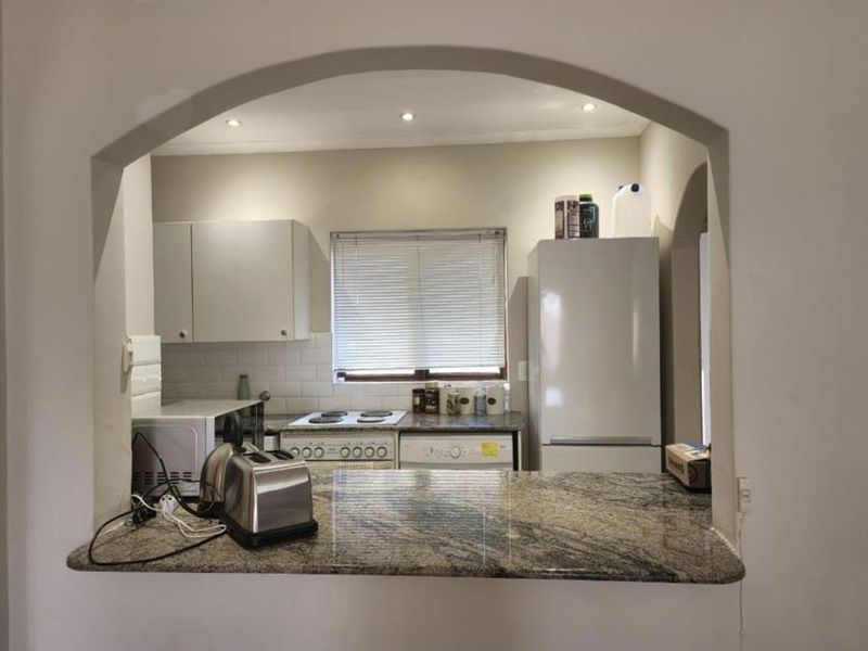 A functional kitchen featuring granite countertops, subway tile backsplash, and an open-plan archway design connecting to the living area.