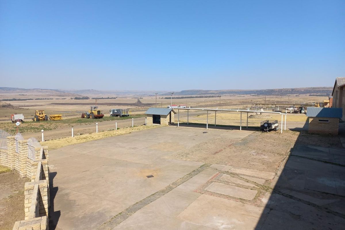 Expansive industrial outdoor yard area featuring a covered parking structure and wide-open space with panoramic rural views.