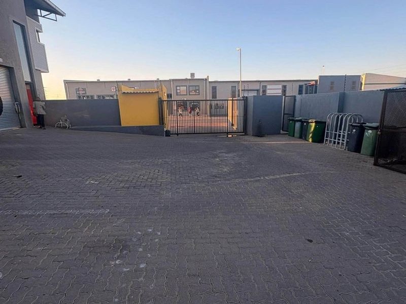 Industrial property exterior featuring a paved driveway, secure perimeter wall, and gated entrance access.