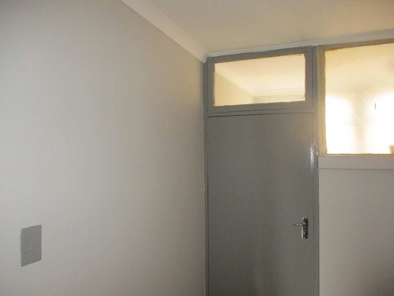 A simple interior hallway featuring a painted door with a transom window above and a standard light switch.