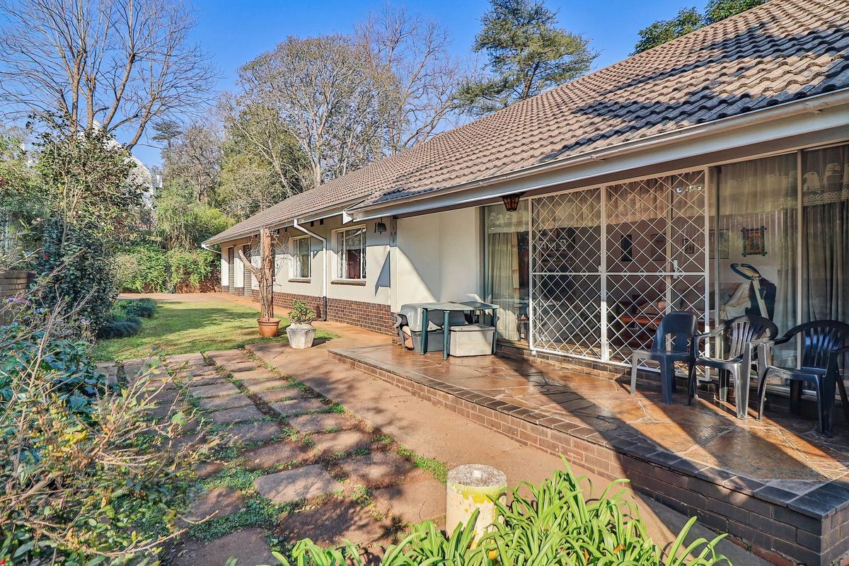 Rear view of the house featuring a paved patio area, brick and plaster facade, and a tiled roof overlooking the garden.