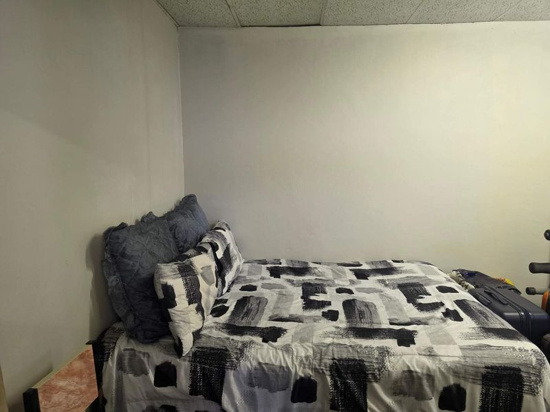 A bedroom featuring a drop ceiling and plain wall finishes, offering a basic space ready for cosmetic updates and personalization.