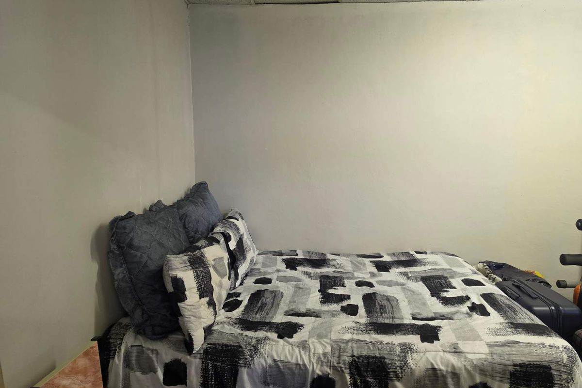 A bedroom featuring a drop ceiling and plain wall finishes, offering a basic space ready for cosmetic updates and personalization.