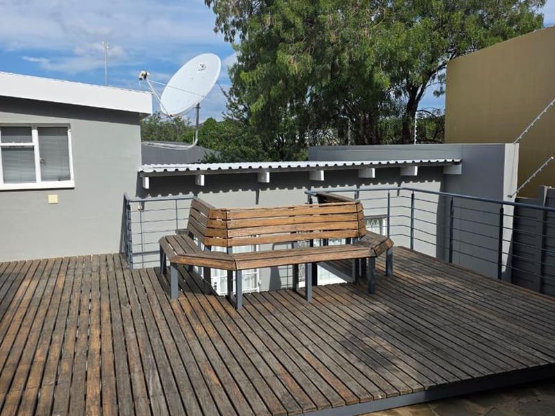 An elevated outdoor timber deck area featuring a metal balustrade and stone paved lower section, suitable for outdoor relaxation.