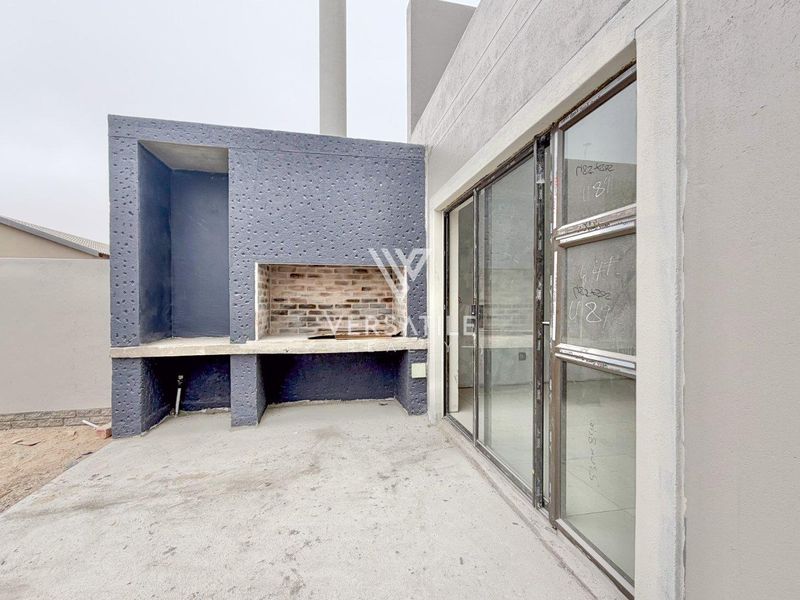 Outdoor patio area featuring a built-in braai and large sliding glass doors, currently in a near-completion construction state.