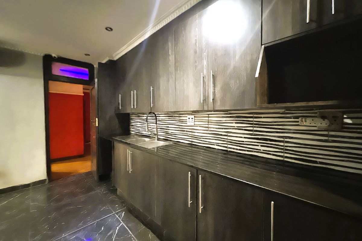 Modern kitchen featuring dark cabinetry, marble-effect floor tiles, and a distinctive striped backsplash, providing a sleek and contemporary workspace.