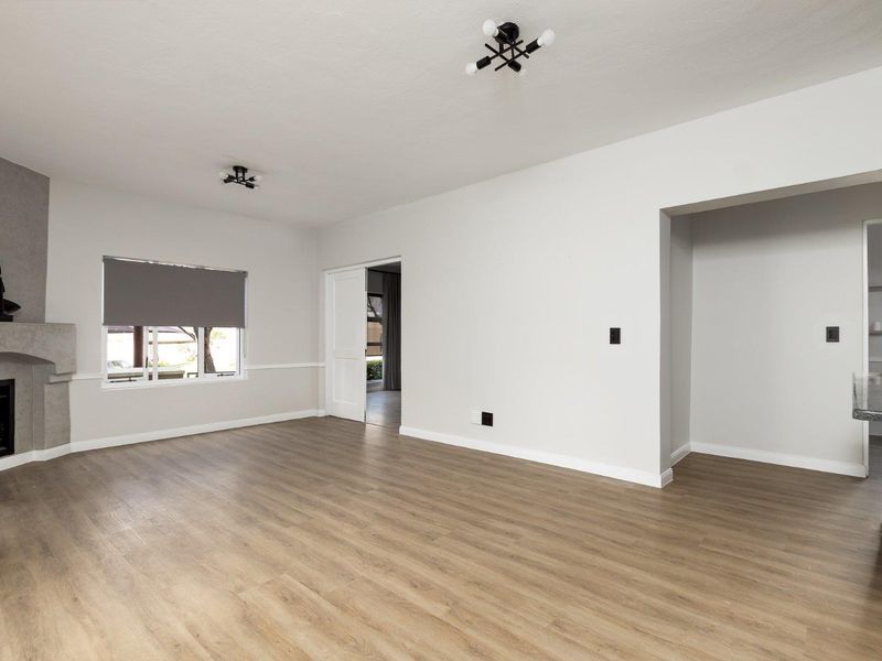 Spacious living room featuring modern laminate flooring, a fireplace, and neutral finishes, offering a bright and versatile open-plan layout.