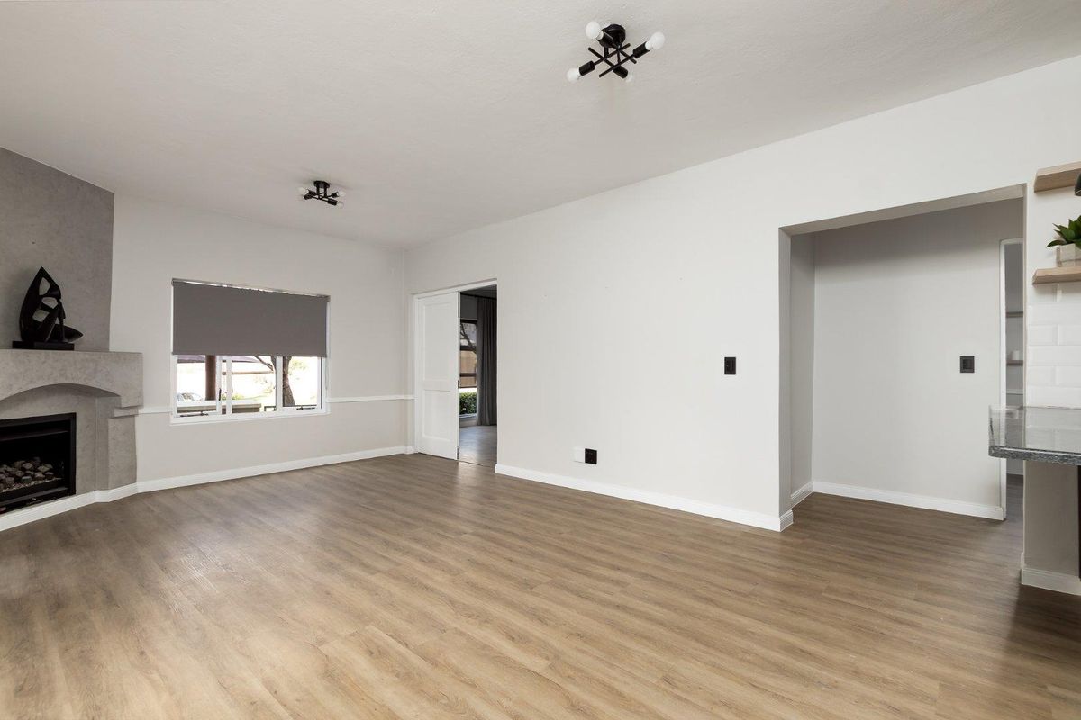 Spacious living room featuring modern laminate flooring, a fireplace, and neutral finishes, offering a bright and versatile open-plan layout.