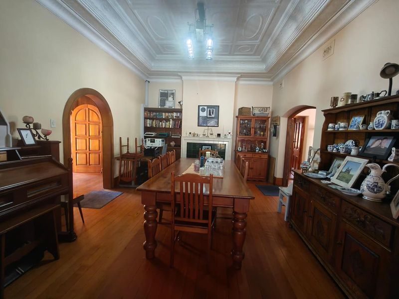 Spacious dining room featuring original hardwood timber flooring, an ornate pressed metal ceiling, and a classic fireplace with tiled surround.
