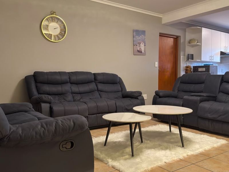 Open plan living area featuring tiled flooring and a functional kitchen space with built-in cabinetry and an extractor fan.
