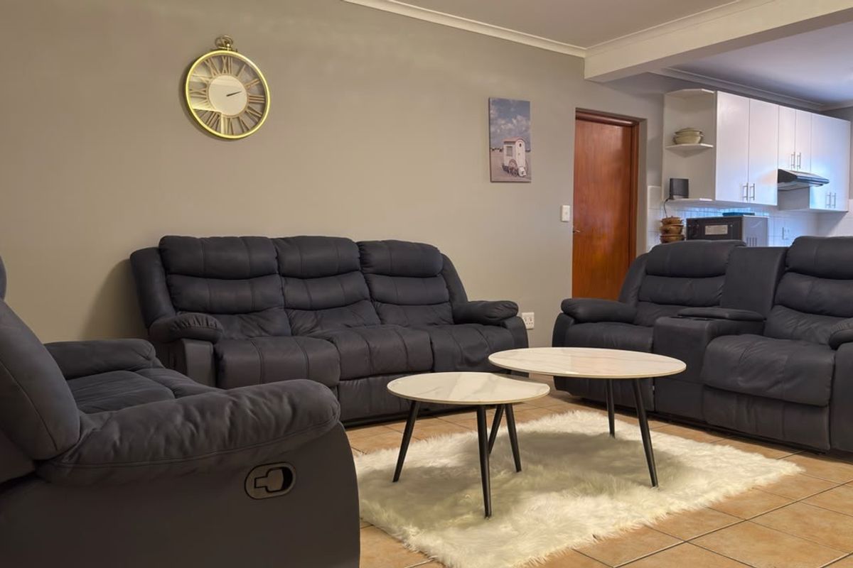 Open plan living area featuring tiled flooring and a functional kitchen space with built-in cabinetry and an extractor fan.