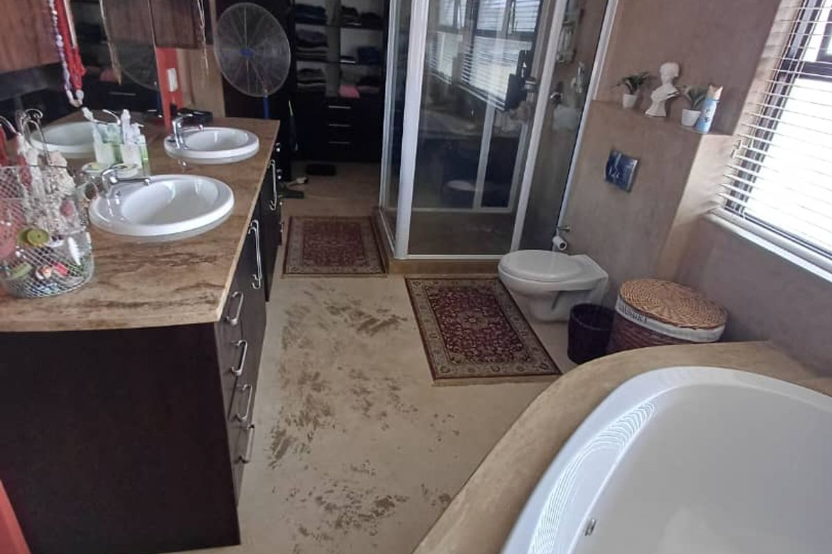 Spacious bathroom featuring a large corner soaking tub, double vanity with dark cabinetry, a glass-enclosed shower, and a wall-mounted toilet.