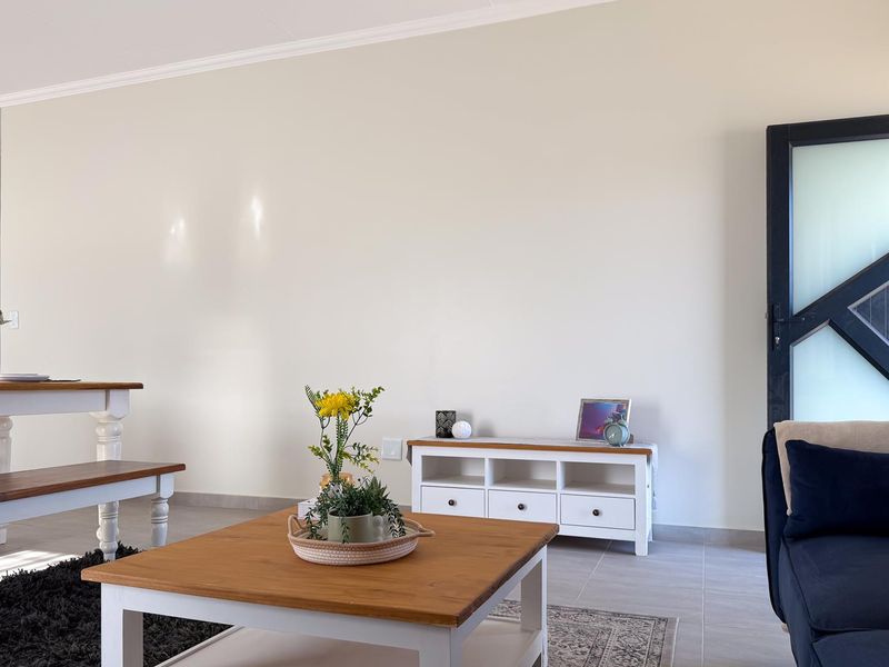 A bright and well-maintained living area featuring neutral walls, tiled flooring, and a contemporary feature door.