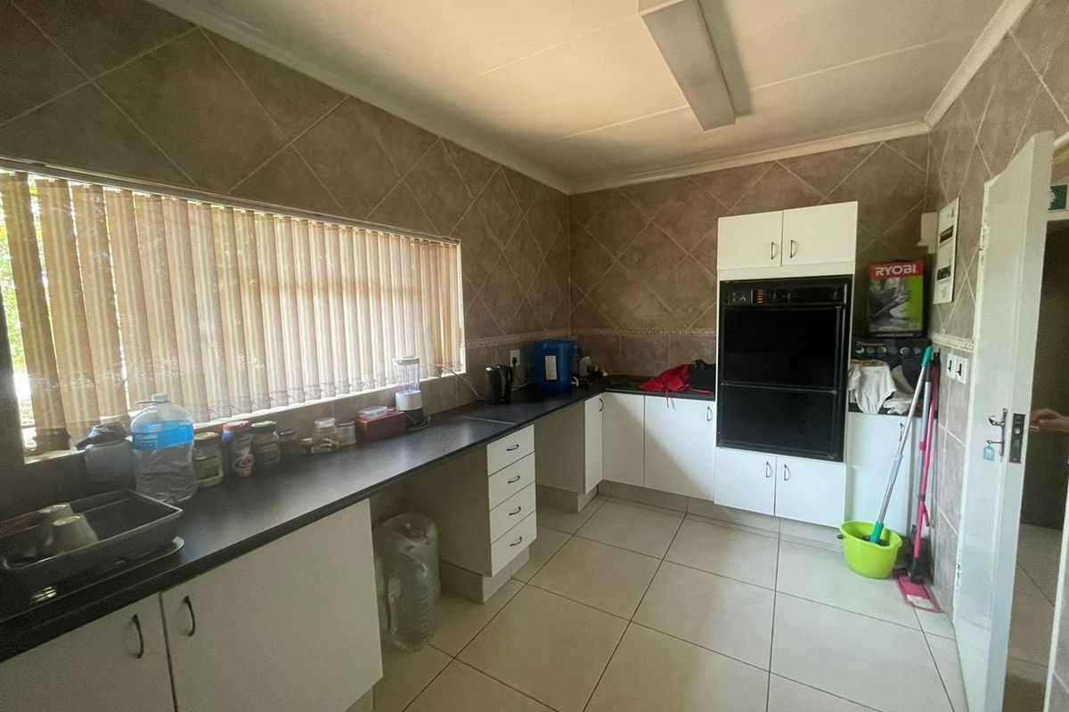 A functional kitchen featuring white cabinetry, dark countertops, built-in oven, and tiled flooring with large windows providing natural light.