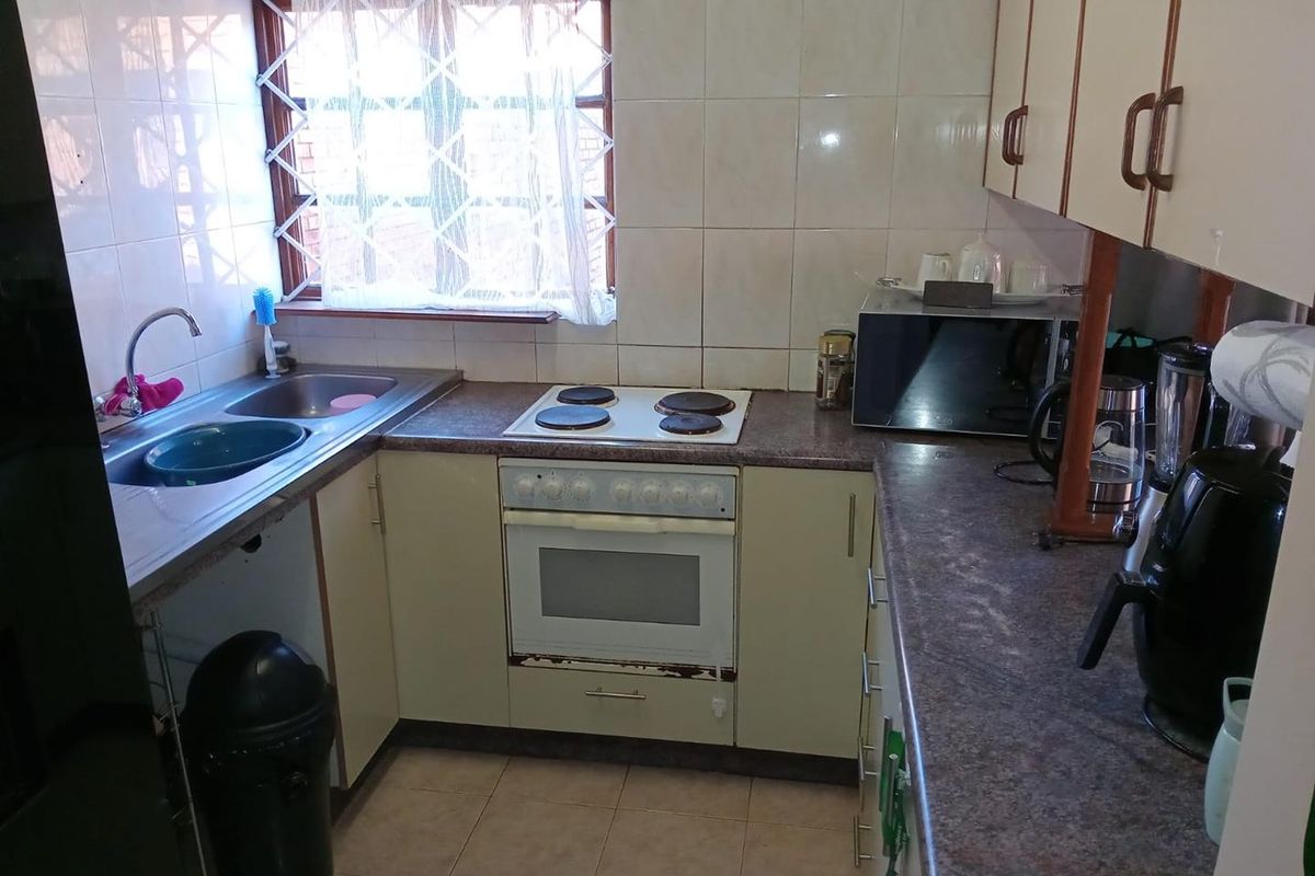 A functional kitchen featuring built-in cabinetry, laminate countertops, a stainless steel double sink, and a built-in electric stove and oven combination.