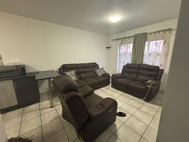 A living room featuring ceramic floor tiles, built-in cabinetry, and window security bars, offering a functional and lived-in space.