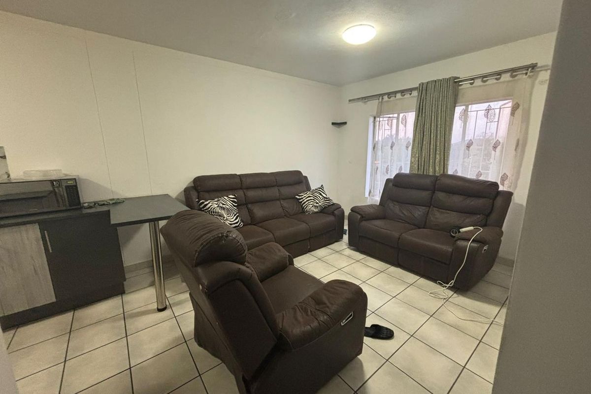 A living room featuring ceramic floor tiles, built-in cabinetry, and window security bars, offering a functional and lived-in space.